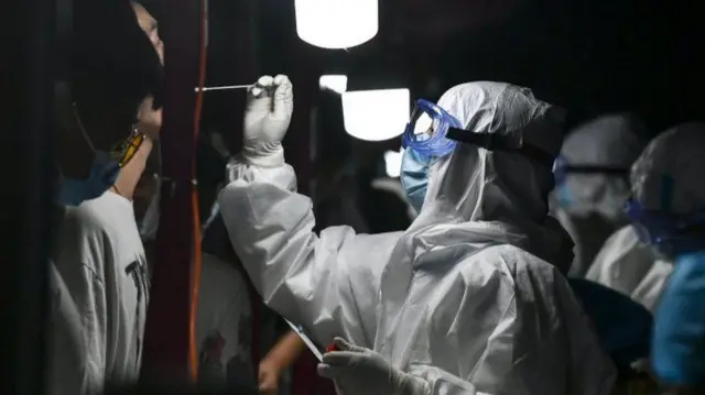 A medical worker collects swab from a resident for nucleic acid testing at dawn