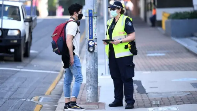 Police check a member of the public for compliance with lockdown orders in central Brisbane, Queensland, Australia