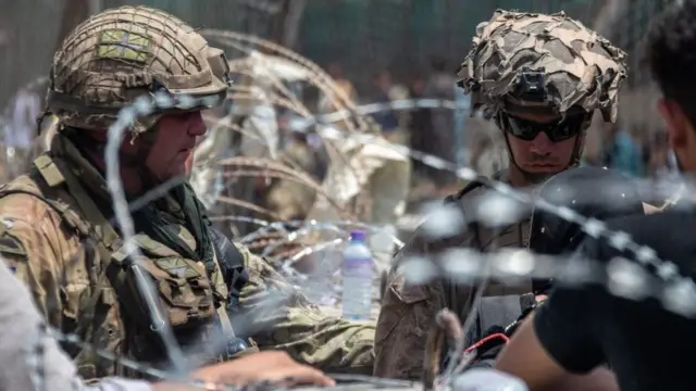 Soldiers stand in front of barbed wire at Kabul airport