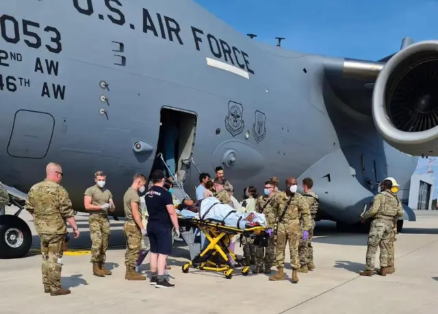 Medical staff help the woman off the aircraft