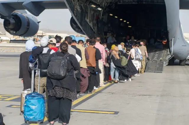 Evacuees assemble before boarding a C-17 Globemaster III during an evacuation at Hamid Karzai International Airport, Afghanistan, August 18, 2021