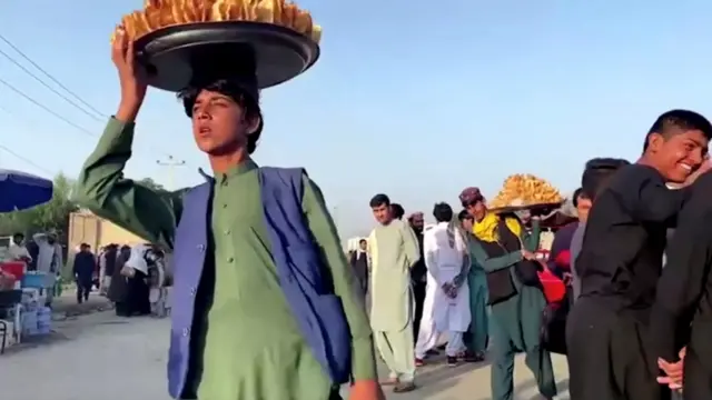 Traders sell food amongst the crowd outside the airport