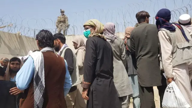 Afghans hoping to get onto the airfield crowd the airport entrances