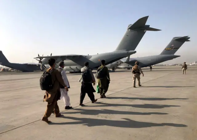 People lining up to board a military aircraft at Kabul airport