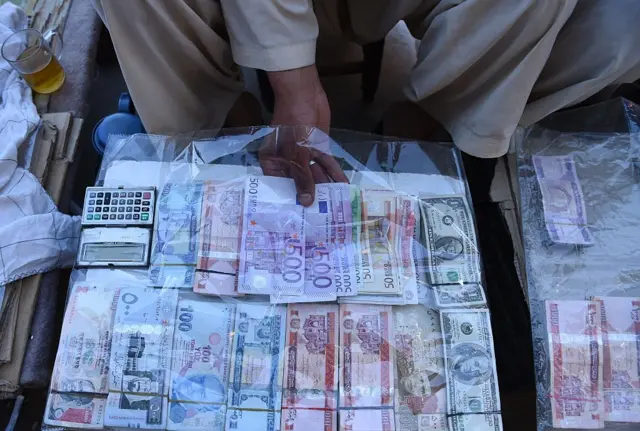 Afghan men wait for customers at a money market in Kabul on May 19, 2015