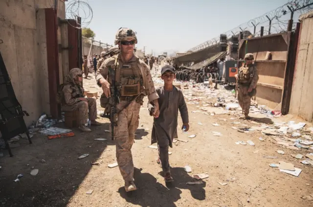 A US marine holds hands with an Afghan boy outside Kabul airport