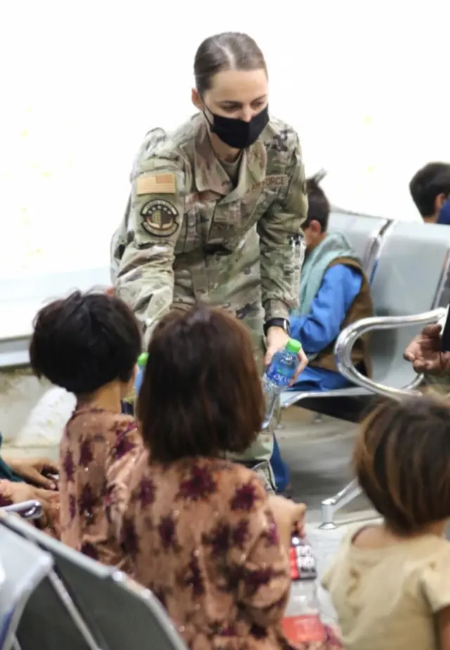 A US military officials gives water to children evacuated from Afghanistan in Kuwait City, Kuwait. Photo: 24 August 2021