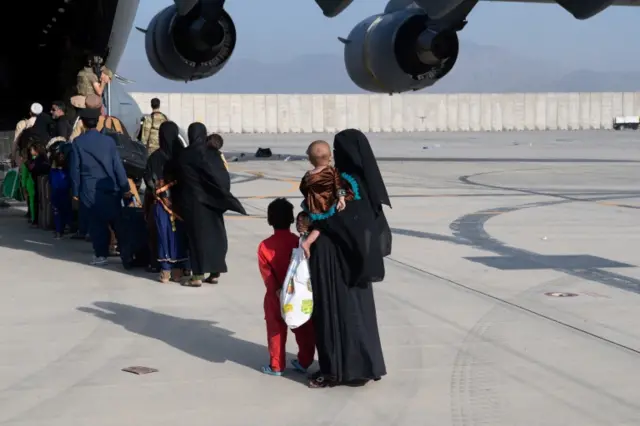 Afghan nationals - many with young children - board a US military plane at Kabul airport, Afghanistan