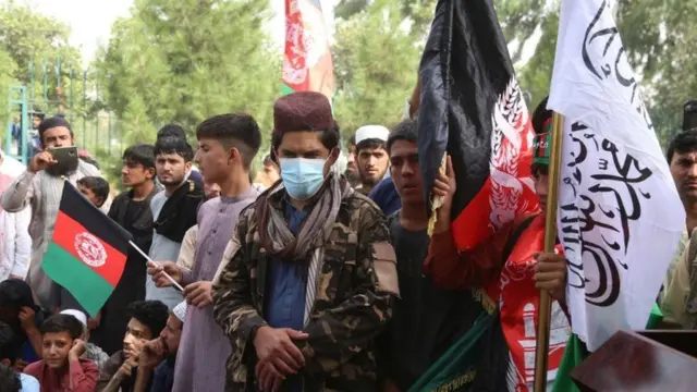 A group of men holding Afghan and Taliban flags