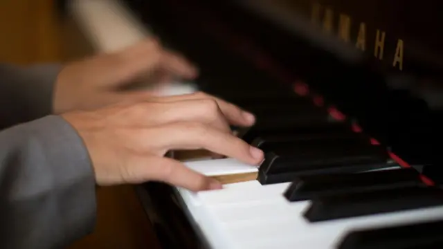 Hands on a piano keyboard