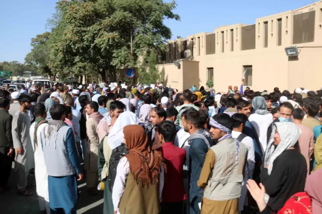 Crowds of people wait outside Kabul airport.