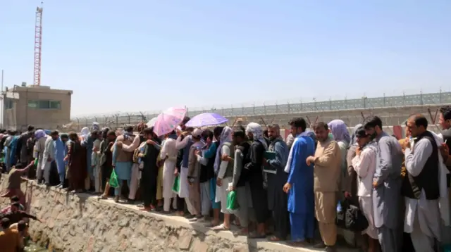 Afghans struggle to reach the foreign forces to show their credentials at Hamid Karzai International Airport, in Kabul, Afghanistan, 26 August