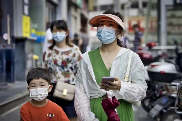 People wearing face masks walk on a street in Shanghai, China