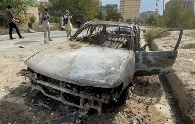 Afghan men take pictures of a vehicle from which rockets were fired, in Kabul, Afghanistan August 30, 2021