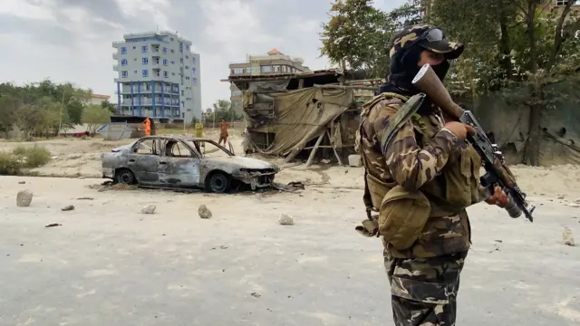 A Taliban fighter stands guard near a vehicle which was used to fire rockets at Kabul airport.