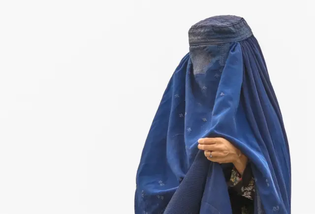 A displaced woman in Kabul wears a burka