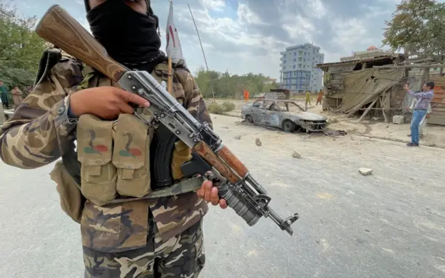 An Armed Taliban fighter stands guard near a vehicle that is believed to have been used in a rocket attack on Kabul airport. Photo: 30 August 2021