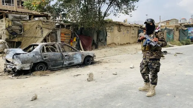 Taliban stands guard near a vehicle which was used to fire rockets at the Hamid Karzai International Airport in Kabul