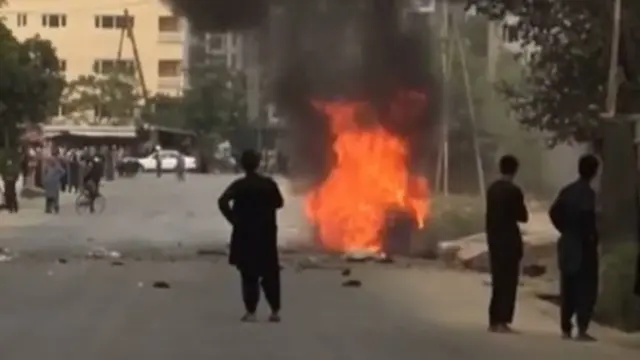 People gather around remnants of flames from cars where rockets towards Kabul's airport were fired from but were intercepted by a missile defence system. Photo: 30 August 2021