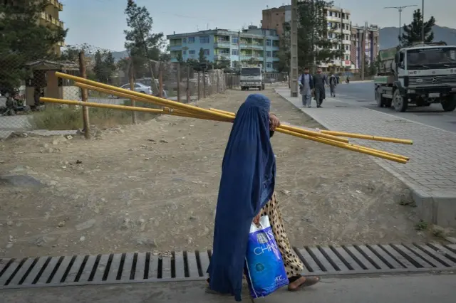 A burka-clad Afghan woman walks along a path in Kabul on 30 August 2021