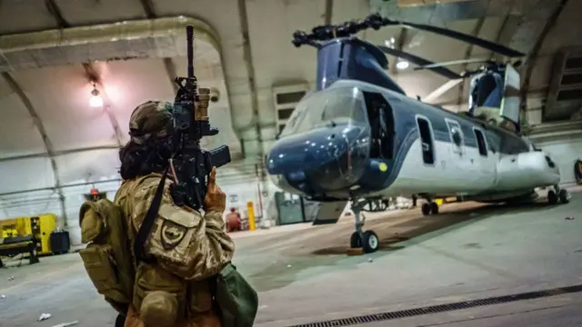 A Taliban fighter inspects a US military helicopter left at Kabul airport. Photo: 31 August 2021