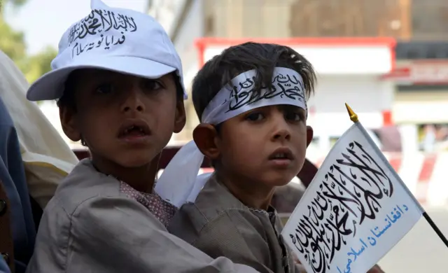 Boys wearing a bandana and a cap with the Taliban flag are seen in a march in Kandahar on August 31, 2021.