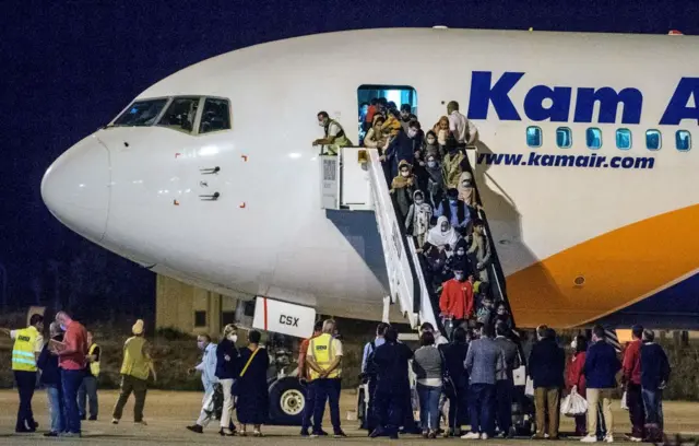 Afghan refugees step off a plane upon arrival at Skopje International Airport