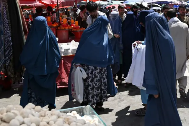 Burqa-clad women shop at market in downtown Kabul