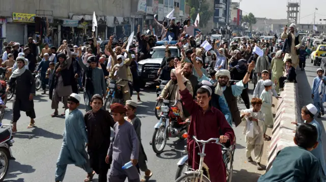 Taliban supporters shout slogans and wave Taliban flags as they march along a street in Kandahar on August 31, 2021.