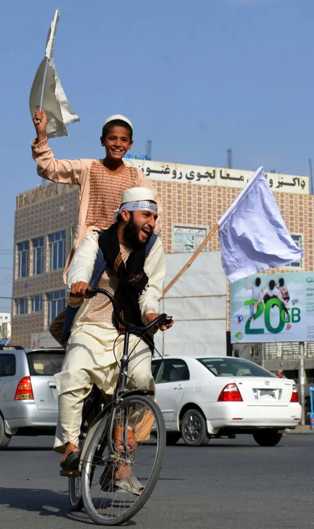 People supporting the Taliban ride a motorcycle in Kandahar.