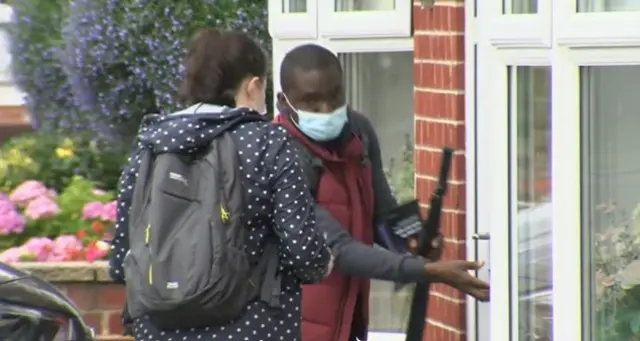 Two members of a government team knock on door of house