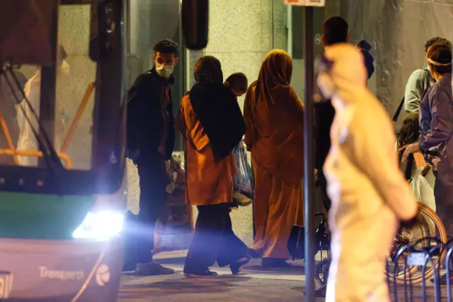 A family, part of more than 90 Australian citizens and Afghan nationals who were evacuated from Afghanistan, steps off a bus as they arrive at a hotel to begin quarantine in Perth