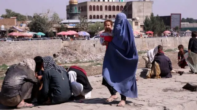 A woman holds her child as she walks along a street in Kabul, Afghanistan. Photo: September 2021