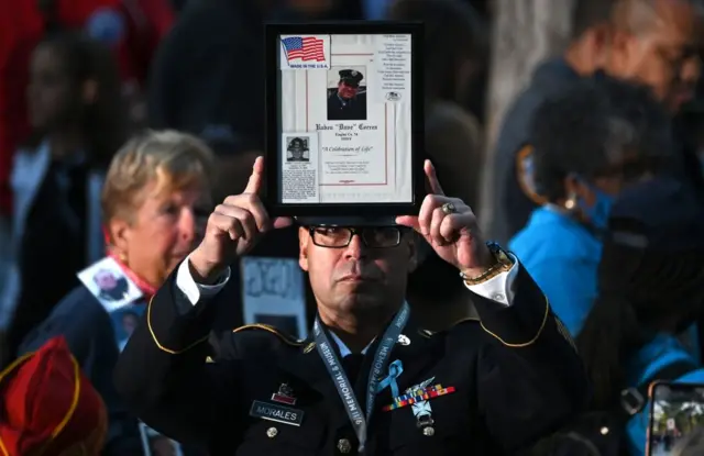 A fireman holds up an image of a fallen colleague ahead of the ceremony