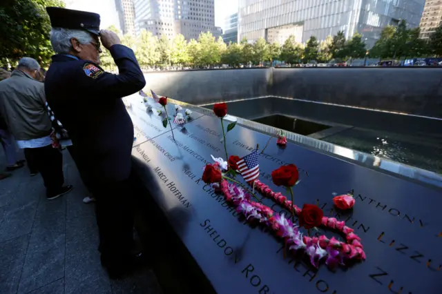 A member of the New York Fire Department stands in salute at Ground Zero's reflecting pool