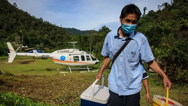 Man taking vaccines from a helicopter