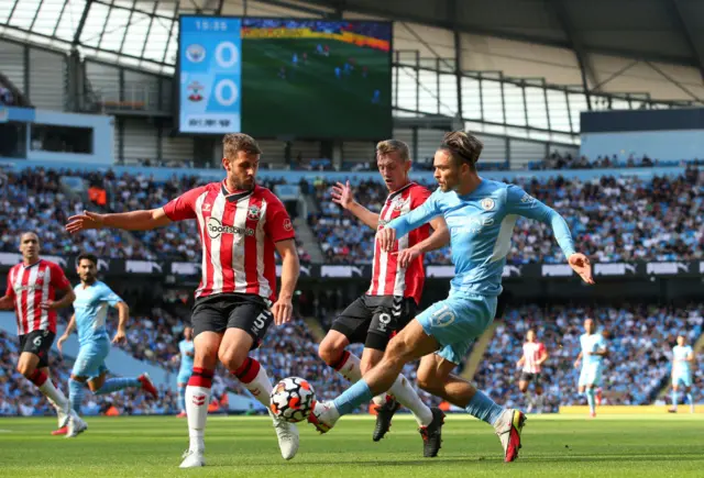 Jack Grealish of Manchester City passes the ball under pressure from Jack Stephens and James Ward-Prowse of Southampton