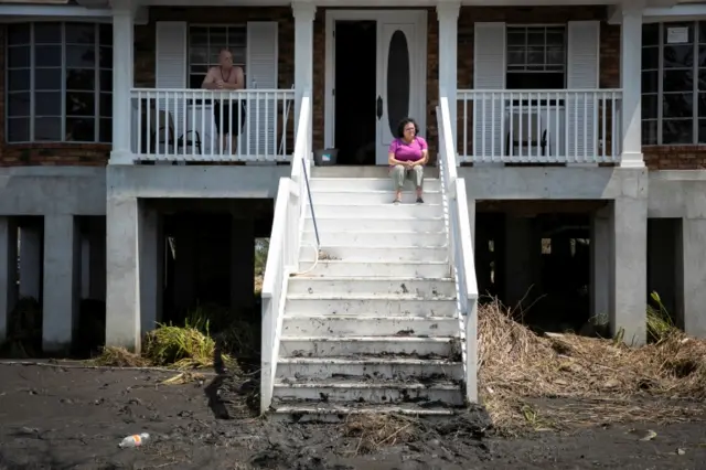 A couple look at their front yard, assessing the damage, in Louisiana