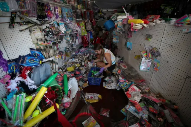 A worker removes flood-damaged merchandise from a store in New York