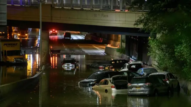 A worker unblocks drains on a street affected by floodwater in Brooklyn, New York early on September 2