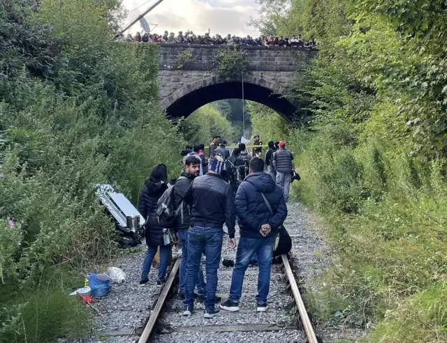 Crowds watch film crew on railway line