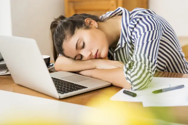 A woman falling asleep at her computer