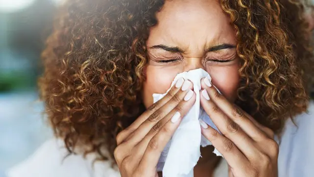 Woman sneezing in a tissue