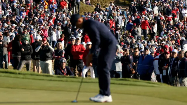 Xander Schauffele putts with fans in the background