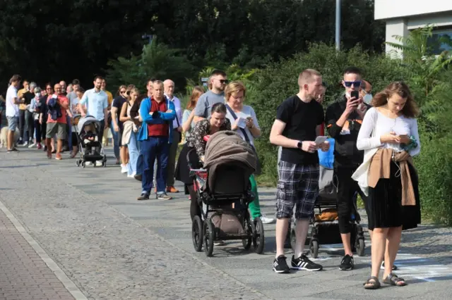 People queue in the street outside a polling station to vote during the general elections, in Berlin, Germany, September 26, 2021