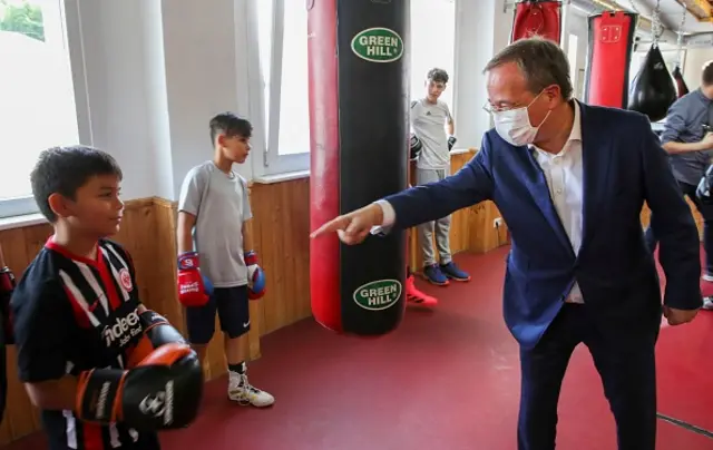 Armin Laschet points to a young boy during his visit to a boxing camp