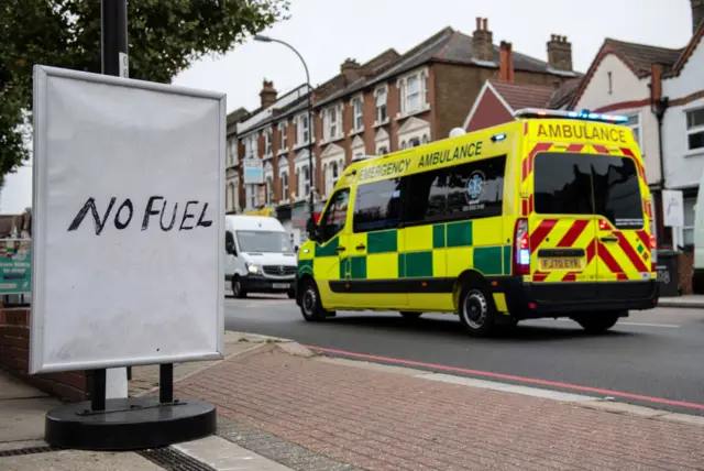 An ambulance passing a petrol station