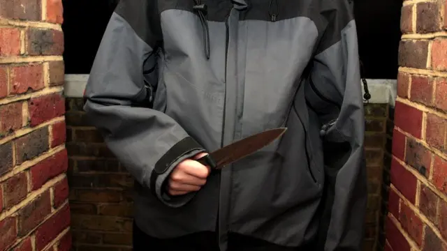 A young person holding a knife