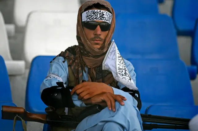 A Taliban fighter watches the Twenty20 cricket trial match being played between two Afghan teams 'Peace Defenders' and 'Peace Heroes' at the Kabul International Cricket Stadium in Kabul on September 3, 2021.