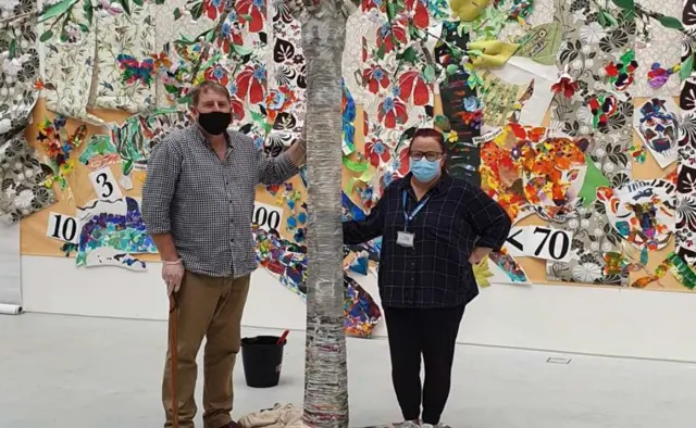 Partly assembled memorial tree with two people standing next to it